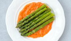 Unos espárragos sobre salsa romesco.