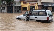 Un hombre trata de salir de su vehículo al verse sorprendido por la riada en la capital de la región griega de Magnesia, Volos.
