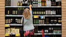 Una clienta coge una botella de aceite de oliva en un supermercado en España.