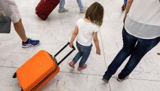 Una niña arrastra su maleta de mano por un aeropuerto en Europa.