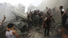 Un grupo de palestinos recoge el cadáver de una persona entre los restos de un edificio destruido por los bombardeos de Israel.