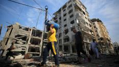 Un grupo de hombres carga con bombonas de butano por las calles destruidas de Gaza.