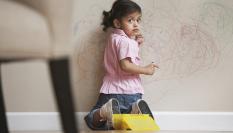 Imagen de archivo de una niña pillada pintando una pared.