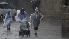 Varias personas caminan con chubasqueros bajo una fuerte tormenta, en una imagen de archivo