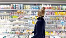 Una mujer eligiendo yogures en un supermercado.