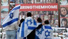 Niños envueltos con la bandera israelí miran los retratos de los civiles secuestrados por Hamás, durante una manifestación en favor de Israel celebrada en la Biblioteca Universitaria Central de Bucarest, el 2 de noviembre.