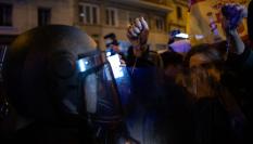 Una asistente a las protestas contra la amnistía en Ferraz sostiene un rosario ante un agente de la Policía.