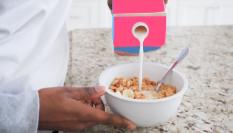 Una persona echando leche en su tazón de cereales