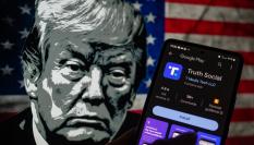 La red social Truth Social en la pantalla de un móvil con el rostro de Trump, dibujado al fondo.