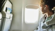 Mujer mirando por la ventanilla en el avión