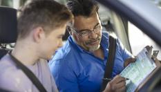 Profesor de autoescuela enseñando a un alumno.