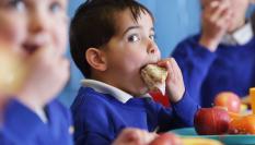 Imagen de archivo de un niño comiendo en el colegio.