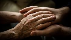 Una mujer sosteniendo las manos de una persona mayor.