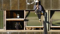 GRAFCAT6961. BARCELONA, 30/11/2023.- Un agente conversa con una ocupa que permanece colgada de la fachada después de que los Mossos hayan conseguido acceder al interior de El Kubo, uno de las dos casas ocupadas en la Bonanova de Barcelona que deben ser desalojadas este jueves, y están en estos momentos inspeccionando las plantas subterráneas y realizando gestiones para asegurar el acceso a las superiores, así como al patio de la Ruïna. Los agentes desplegados en el lugar se están encontrando con una fuerte resistencia de los ocupas, que se han atrincherado para evitar ser desalojados, y desde el interior de las casas, que están comunicadas entre sí, los ocupas han lanzado sacos de escombros, botes de humo y bengalas para dificultar la intervención.