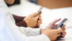 Varios alumnos manejan un móvil en clase