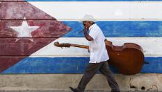 Un músico frente a un mural con la bandera de Cuba.