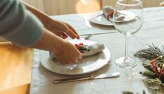 Una persona preparando la mesa para una comida navideña.
