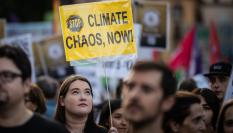 Un joven con una pancarta que pide parar el "caos climático, ya".
