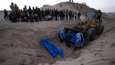 Una excavadora descarga los cuerpos de palestinos muertos en combates con Israel y entregados por el ejército israelí.