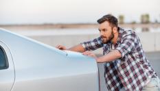 Foto de archivo de un hombre empujando un coche.