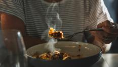 Una persona degustando un plato caliente.