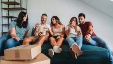 Imagen de archivo de varios jóvenes compañeros de piso, de mudanza, aprovechando una pausa para comer.