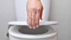 Mano levantando tapa del inodoro