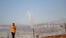 Se disparan cohetes desde la Franja de Gaza (al fondo) mientras un palestino desplazado camina cerca de la frontera palestino-egipcia en el campamento de Rafah, en una imagen de archivo.