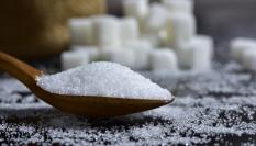 Cucharada de azúcar con terrones de fondo.