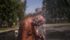 Un hombre se refresca con agua en Madrid en la primera ola de calor del verano de 2023.