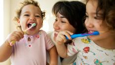 Niños cepillándose los dientes con su madre