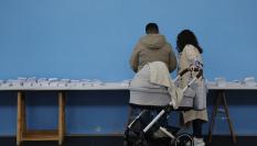 Una pareja escoge una papeleta para ejercer su derecho al voto en el colegio Ames a las afueras de Santiago de Compostela.