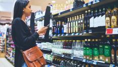 Imagen de una mujer comprobando varias marcas de aceite de oliva en un supermercado.