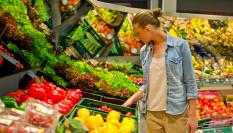 Imagen de archivo de una mujer observando productos frescos en el supermercado.