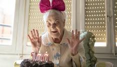 Una mujer sopla las velas en su 100 cumpleaños.