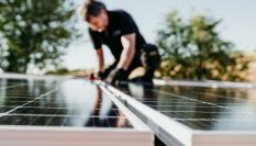 Un técnico instala varios paneles solares en el tejado de una vivienda.