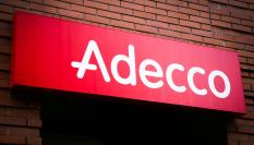 Logotipo de Adecco situado en la puerta de acceso de una oficina de la compañia.