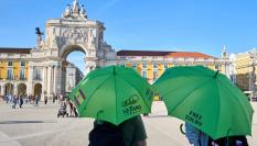 Dos guías esperan la llegada de turistas en la Plaza do Comercio de Lisboa.