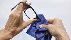 Una persona limpia las gafas con la balleta que entregan en las ópticas.