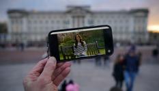 Una persona viendo el anuncio de Kate Middleton frente al palacio de Buckingham.