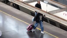Una mujer paseando frente a un tren de Renfe.
