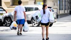 Dos personas cargan sus compras en bolsas de plástico