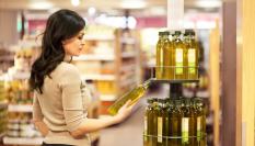 Una mujer examina una botella de aceite de oliva en un supermercado.