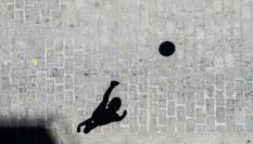 La sombra de un niño jugando con una pelota en una calle