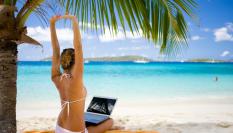 Imagen de una mujer con un portátil en una playa caribeña.