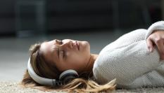 Una joven escuchando música con apariencia triste.