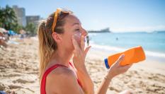 Una mujer aplicándose protector solar facial.