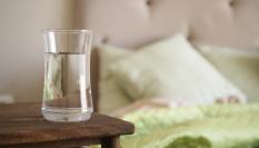 Un vaso de agua en una mesilla.