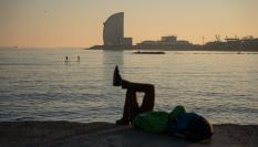 Varias personas disfrutan de un día soleado, junto al mar, en Barcelona