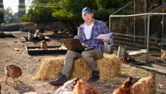 Imagen de archivo de un ganadero consultando su ordenador portátil ante un gallinero.